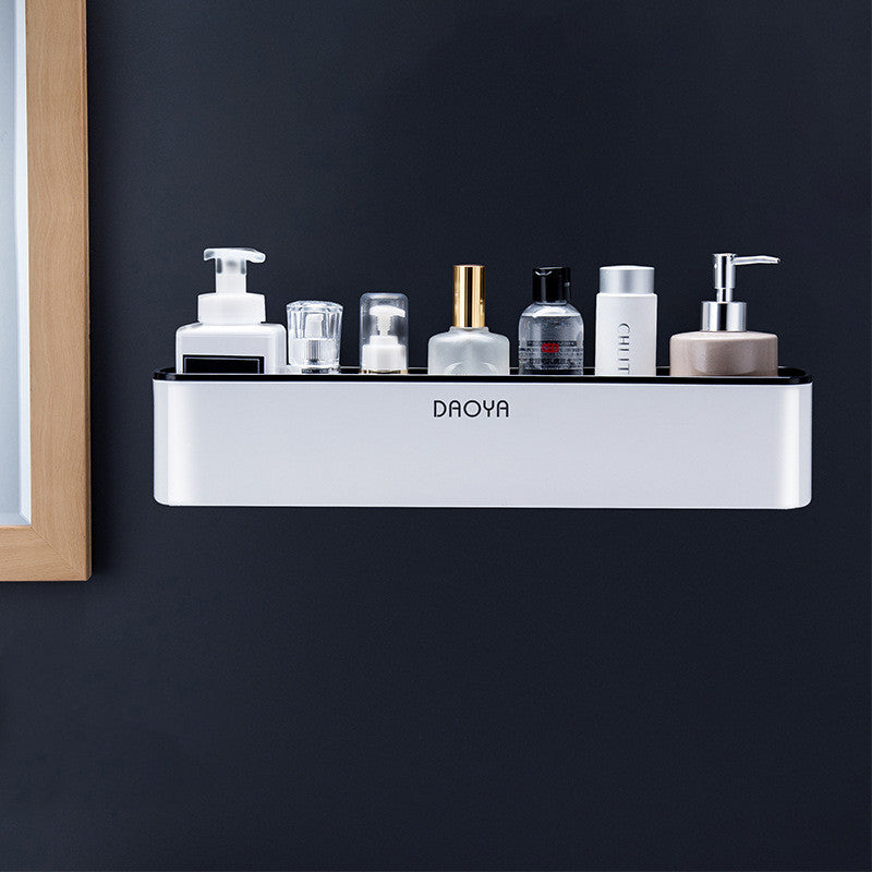Enkele witte wandplank met zwarte rand en diverse flesjes tegen een donkere wand.